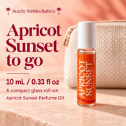 Beachy Bubbles Bath Co Apricot Sunset compact glass roll-on perfume oil, 10 mL / 0.33 fl oz, styled beside a travel pouch.